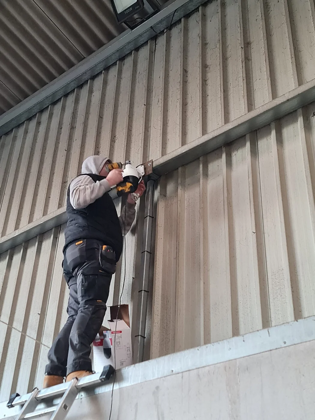 Installer fitting a turret CCTV camera inside an agricultural building